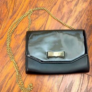 Ted Baker London black clutch in glove and patent leather. Gold bow